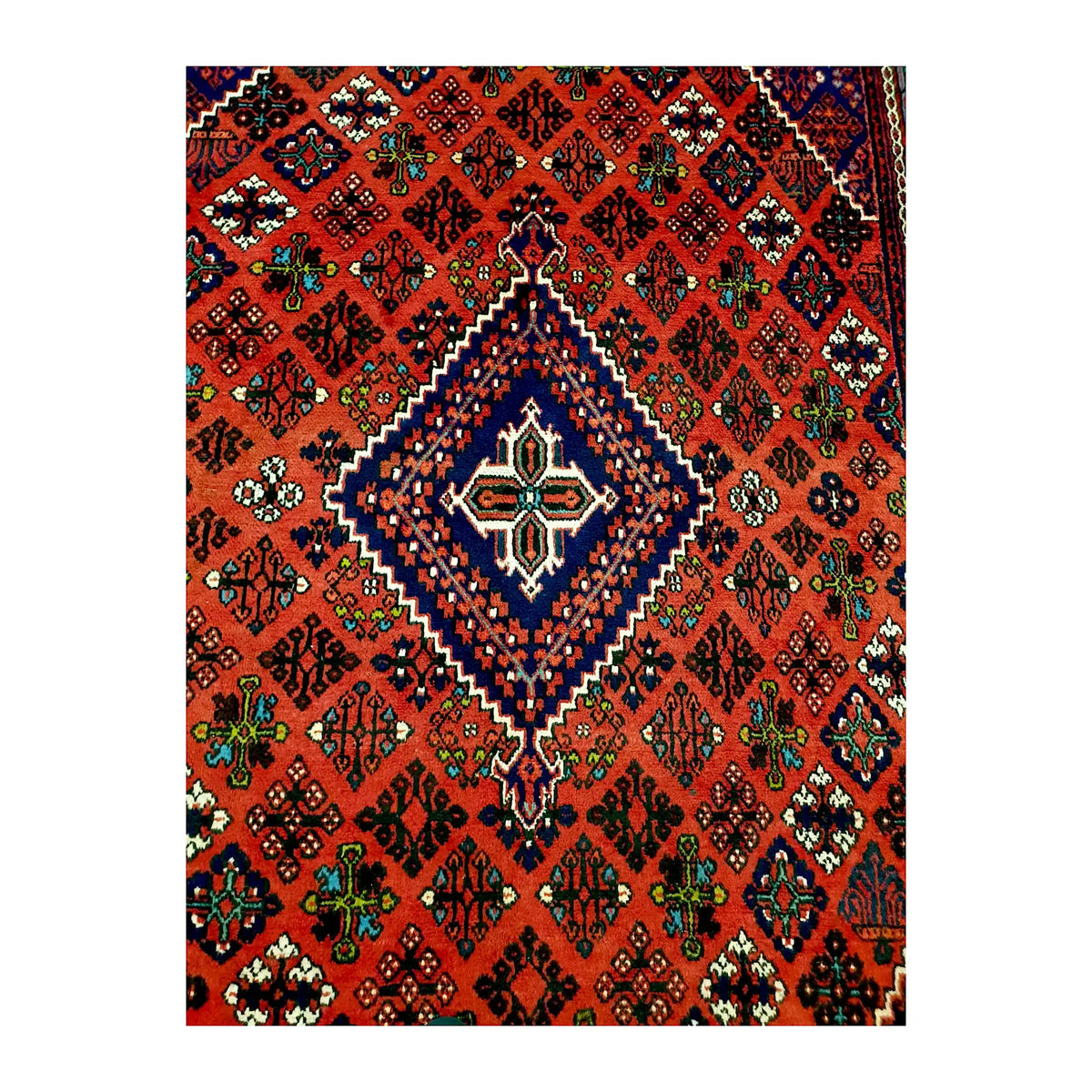 Close view of the stepped navy diamond medallion and multicoloured geometric motifs on the red field