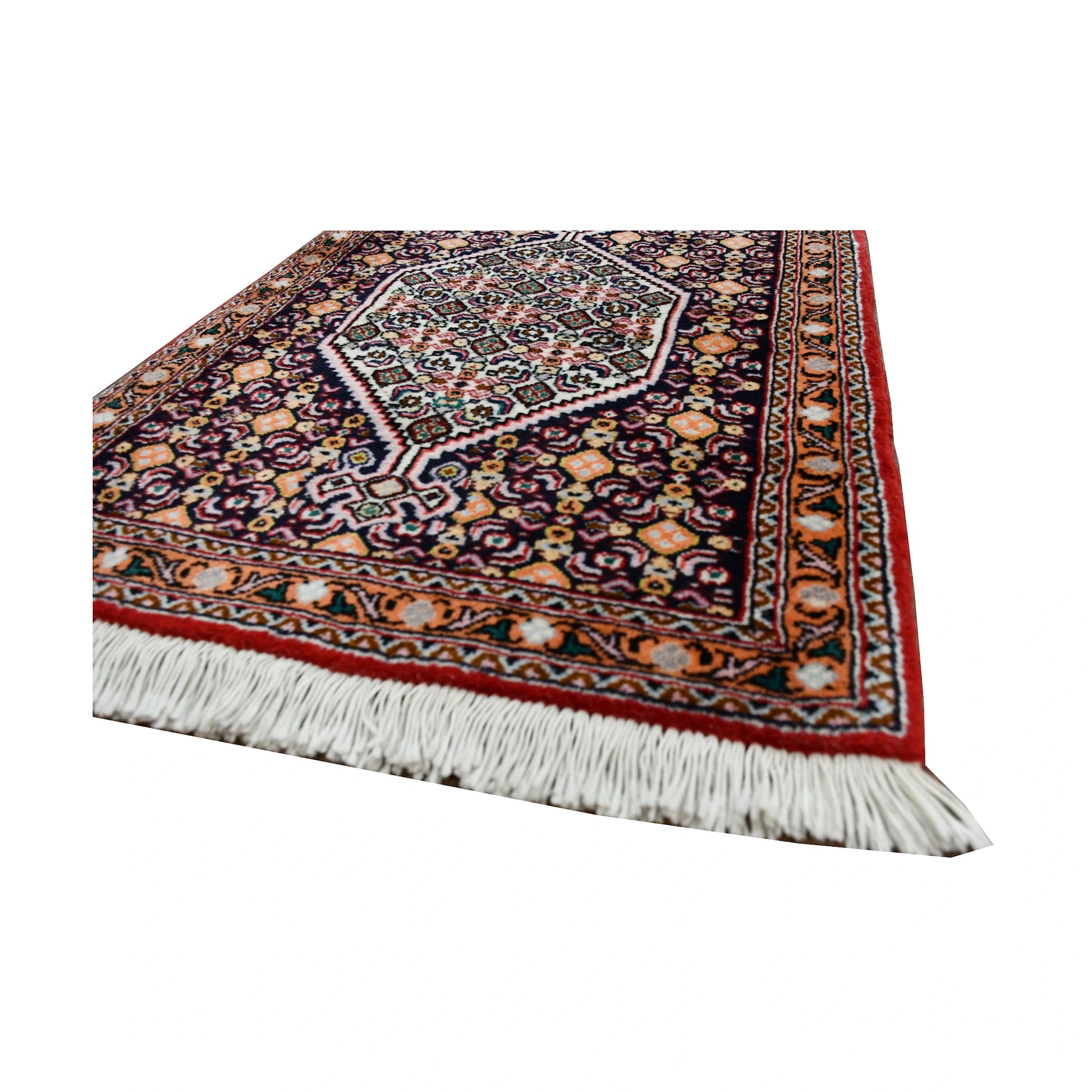 Angled fringe and corner detail of Persian Senneh runner showing dense floral pattern, indigo field and red border