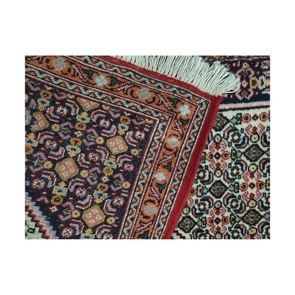 Folded corner detail of Persian Senneh runner showing the back of the rug, fringe and fine front pattern