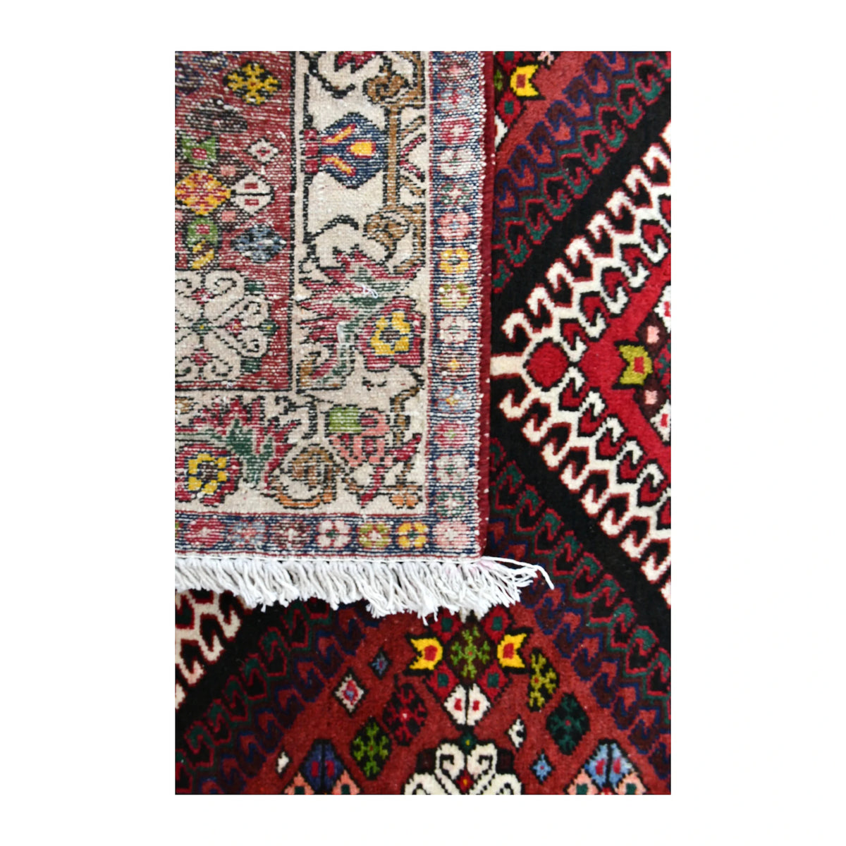 Folded corner of Persian Shiraz runner showing the patterned face, reverse weave and ivory fringe