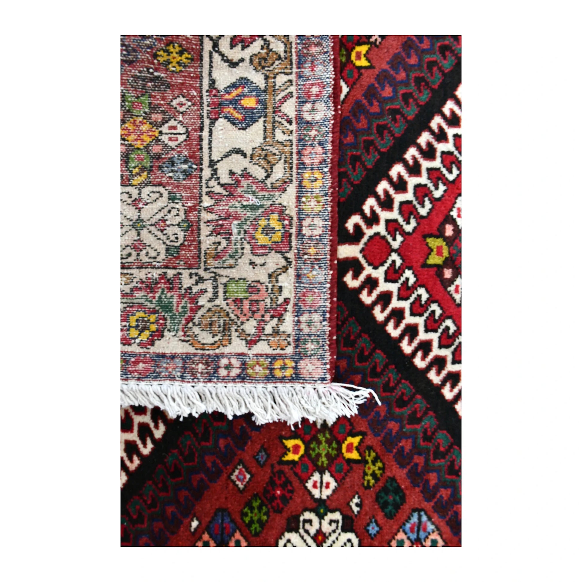 Folded corner of Persian Shiraz runner showing the patterned face, reverse weave and ivory fringe