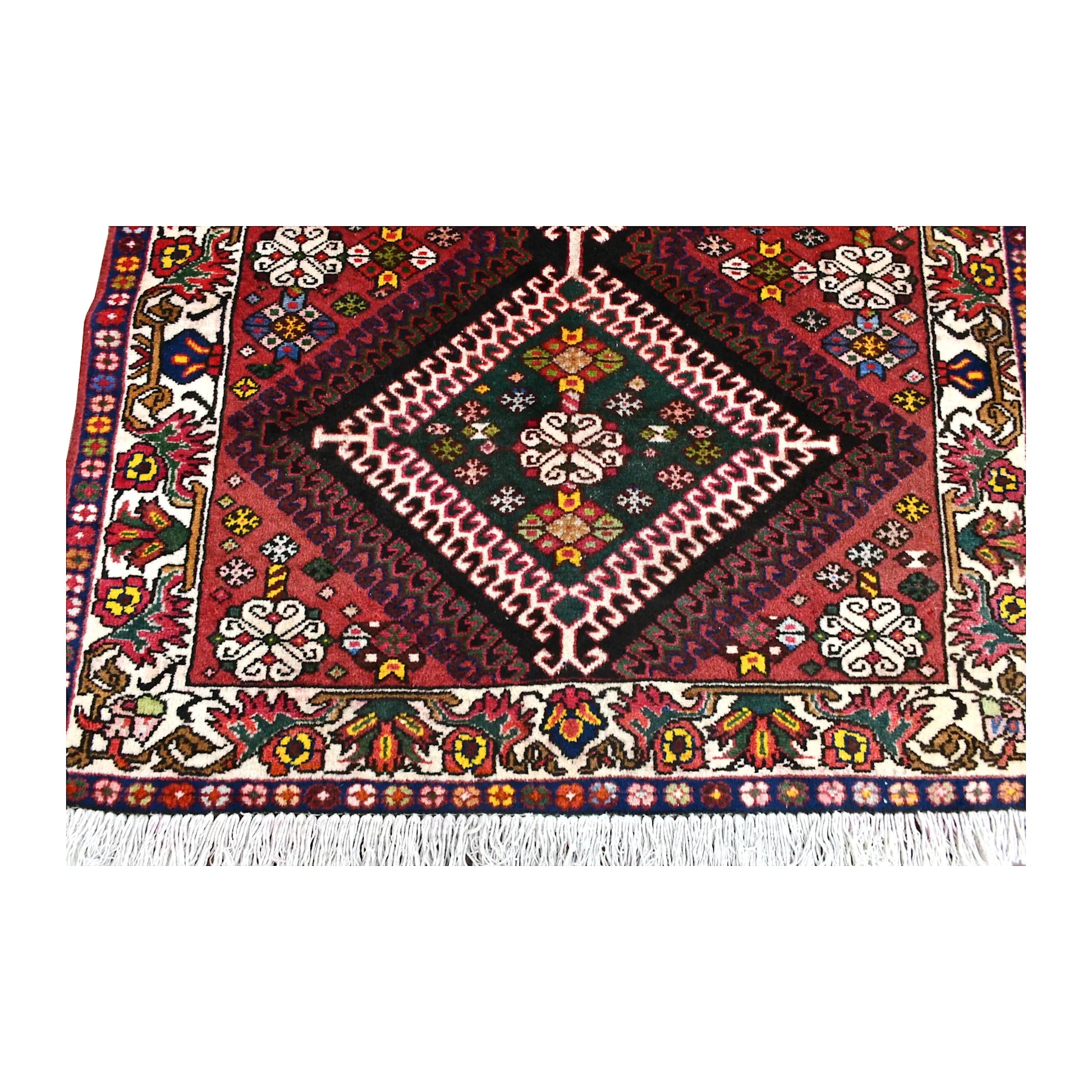 End-section detail of Persian Shiraz runner showing a dark green diamond medallion, deep red field, floral border and fringe