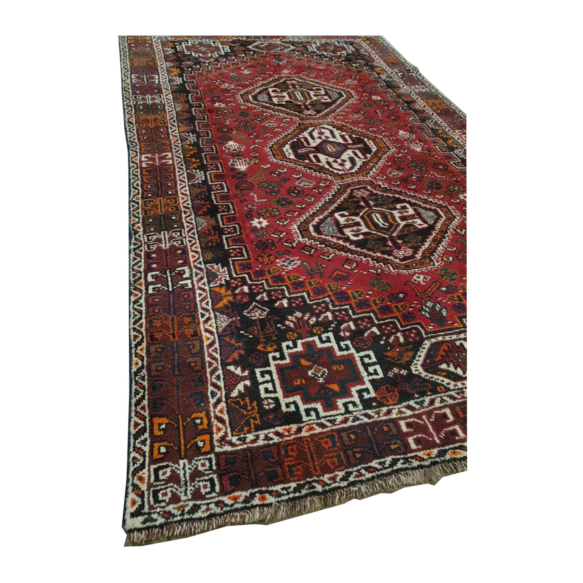 Angled full view of Persian Shiraz wool rug showing the red field, central medallions and layered borders