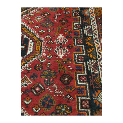 Close-up of Persian Shiraz wool rug showing the red field, symbolic motifs and layered side border