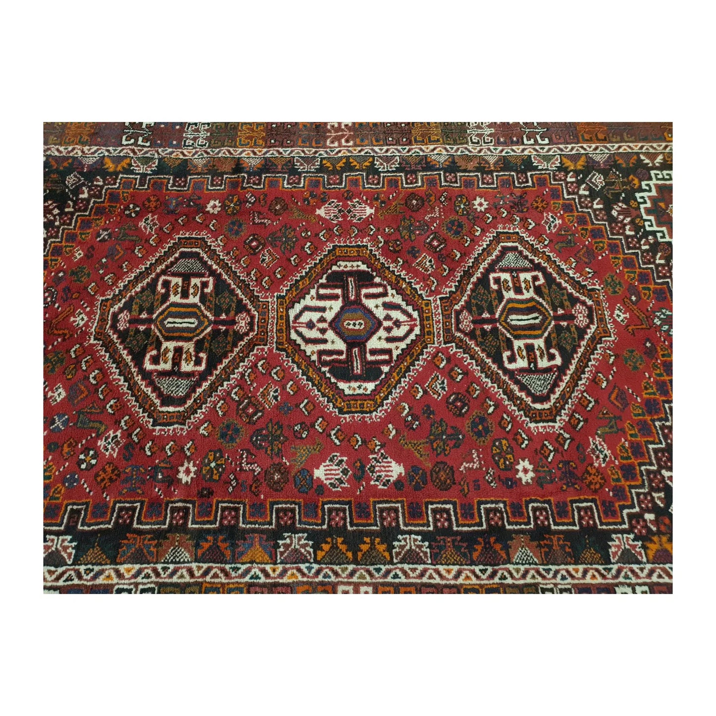 Field detail of Persian Shiraz rug showing three geometric medallions surrounded by small multicolour motifs