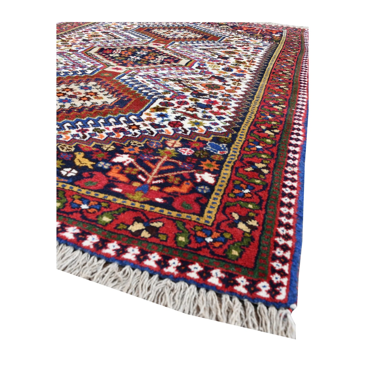 Angled corner of Persian Yalameh rug showing the layered red border, ivory field and fringe