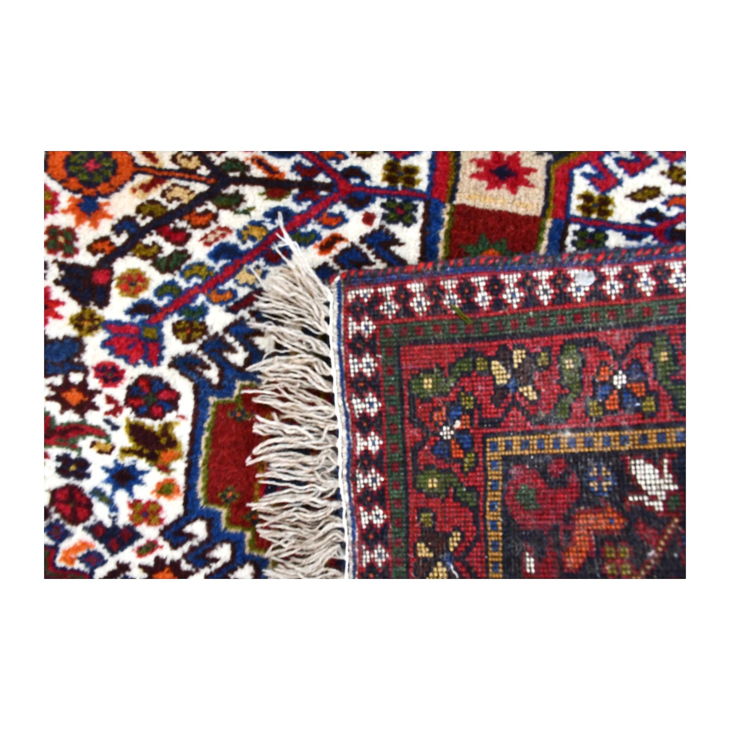 Folded corner of Persian Yalameh rug showing the patterned face, reverse weave and ivory fringe