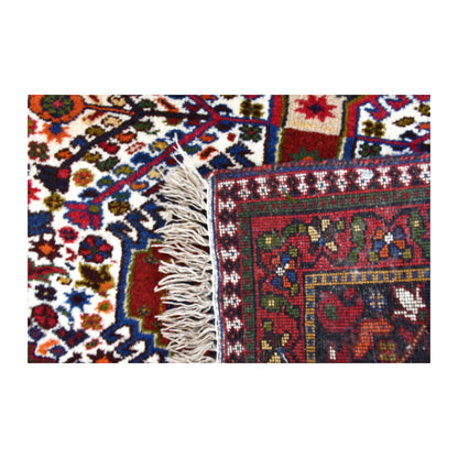 Folded corner of Persian Yalameh rug showing the patterned face, reverse weave and ivory fringe