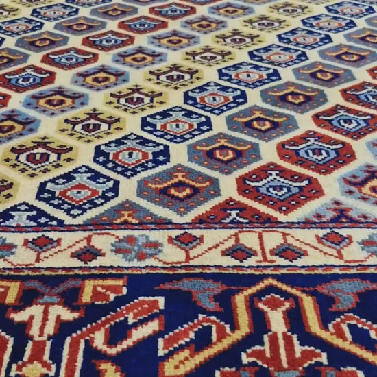 Close-up video of Afghan Shirvan hand-knotted wool rug showing geometric motifs and navy border