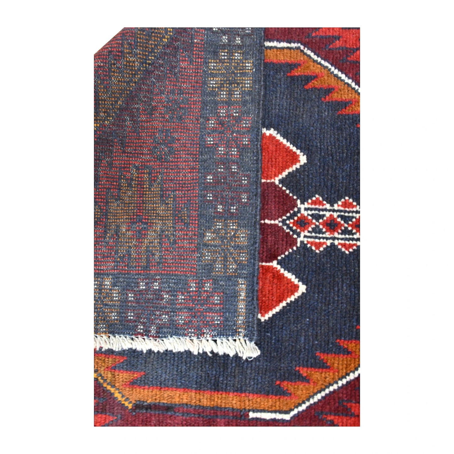 Folded-corner detail of Baluchi rug showing the reverse weave, front pattern and pale fringe