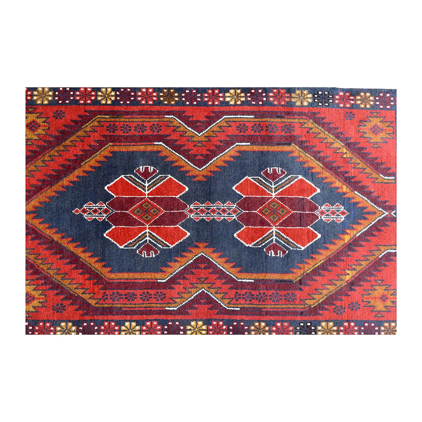 Field detail of Baluchi rug showing two geometric medallions within a red and navy angular design