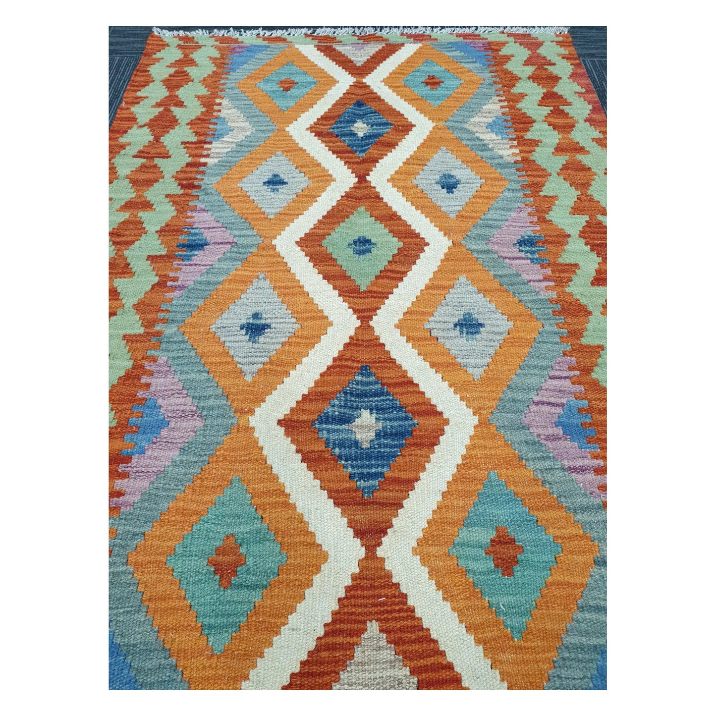 Close-up of Chobi Kilim rug with linked diamond motifs in sky blue, terracotta, teal, lilac, and ivory, 126 x 90 cm