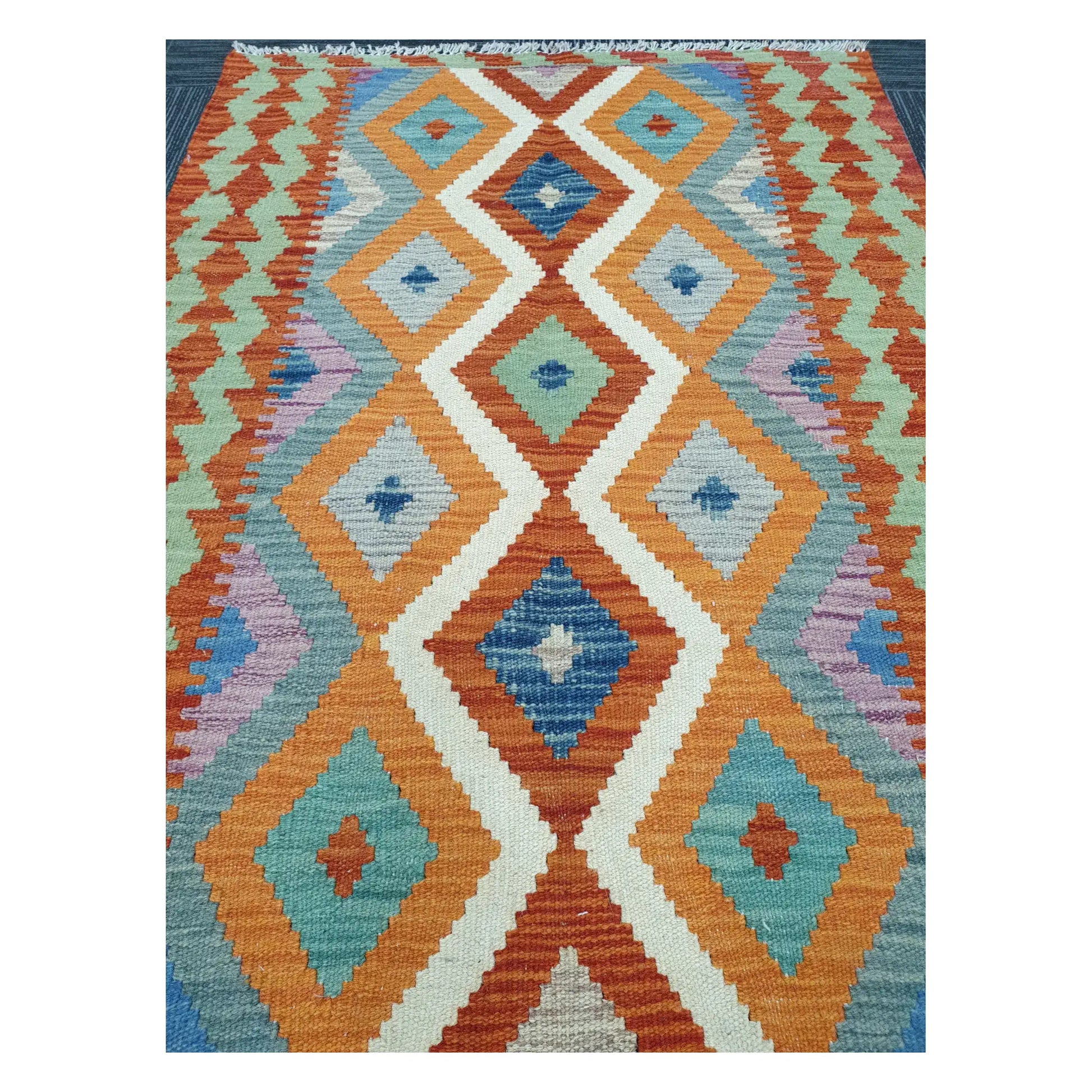 Close-up of Chobi Kilim rug with linked diamond motifs in sky blue, terracotta, teal, lilac, and ivory, 126 x 90 cm
