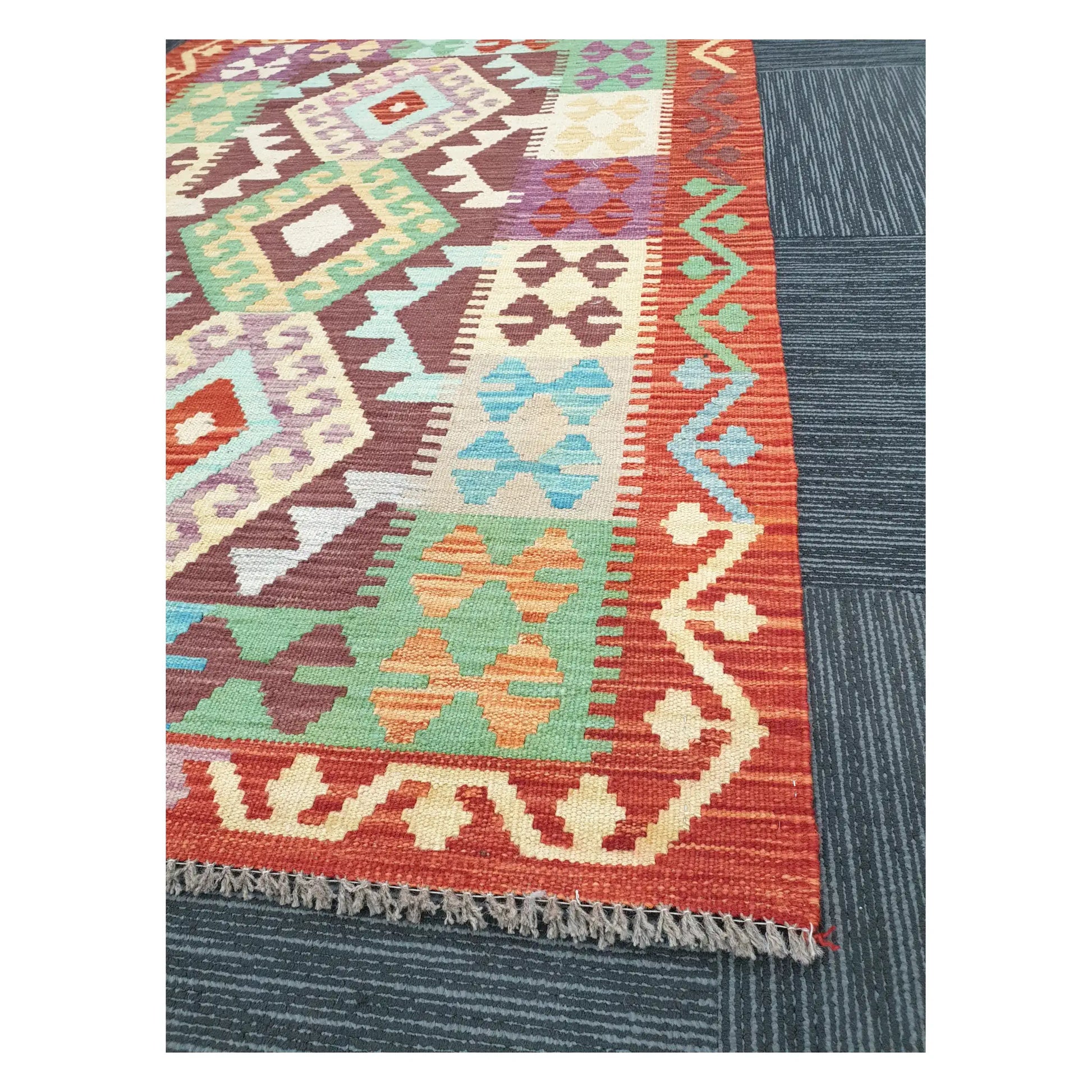 Angled detail of Afghan Chobi Kilim showing fringe, terracotta border, and handwoven geometric pattern, 143 x 107 cm