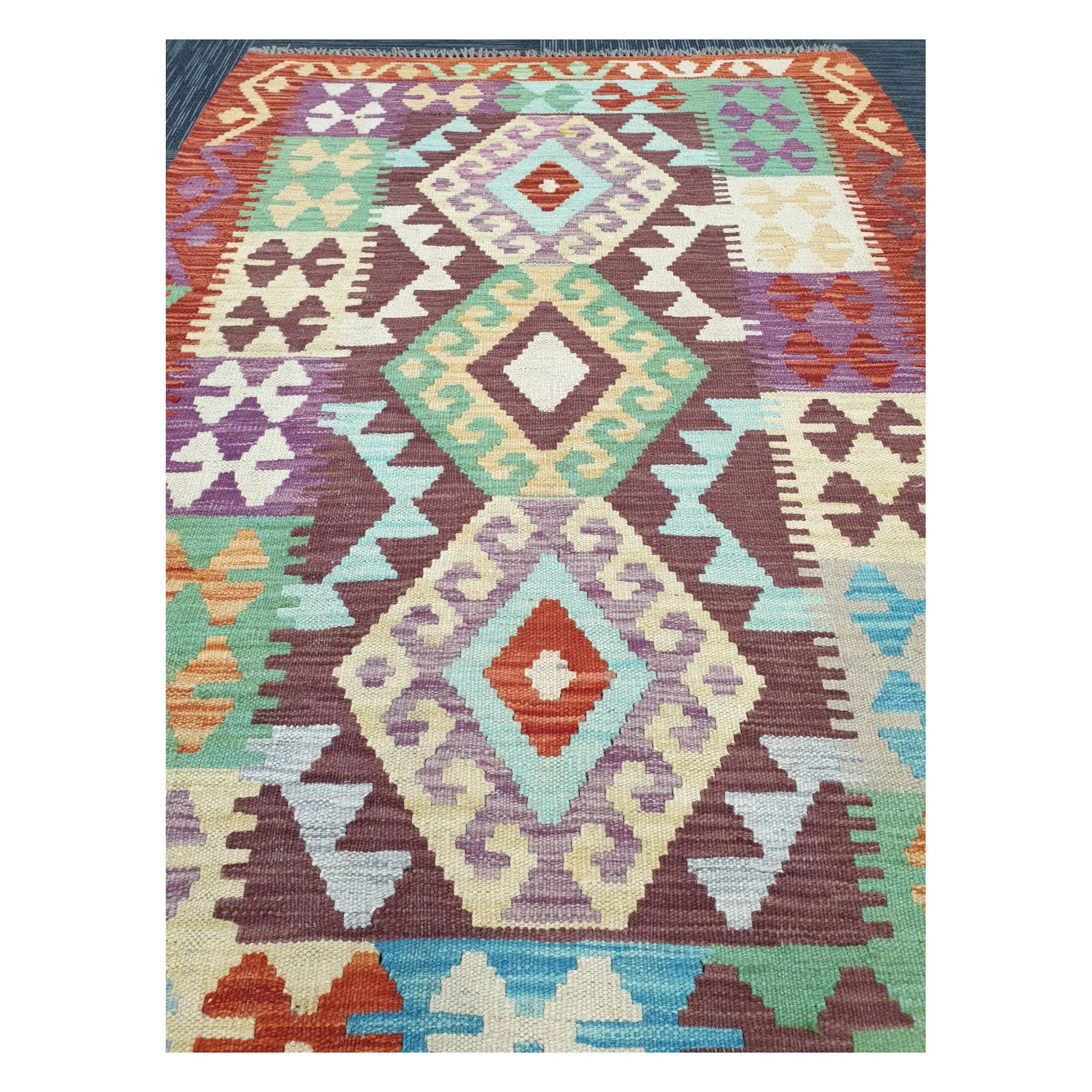 Close-up of Chobi Kilim rug with stacked diamond medallions in ivory, mint, lavender, and rust, 143 x 107 cm