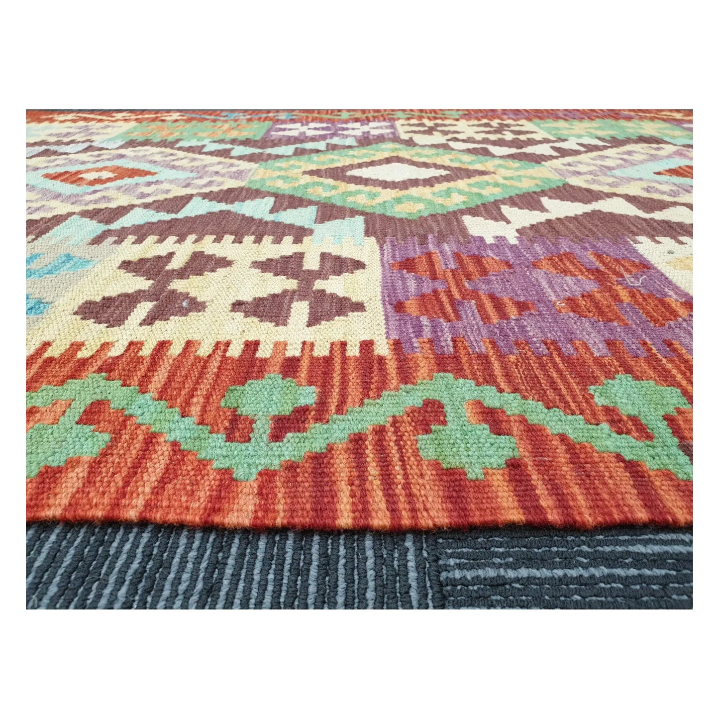 Low-angle close-up of Afghan Chobi Kilim showing wool flatweave texture and multicolour tribal pattern, 143 x 107 cm