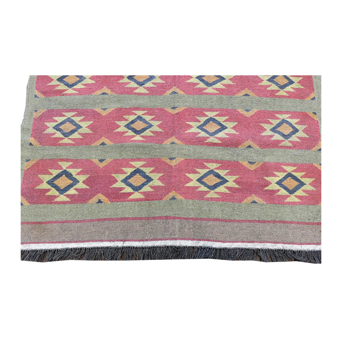 Fringe-end view of Turkish kilim with repeating stars and diamonds across pink bands above the plain end border