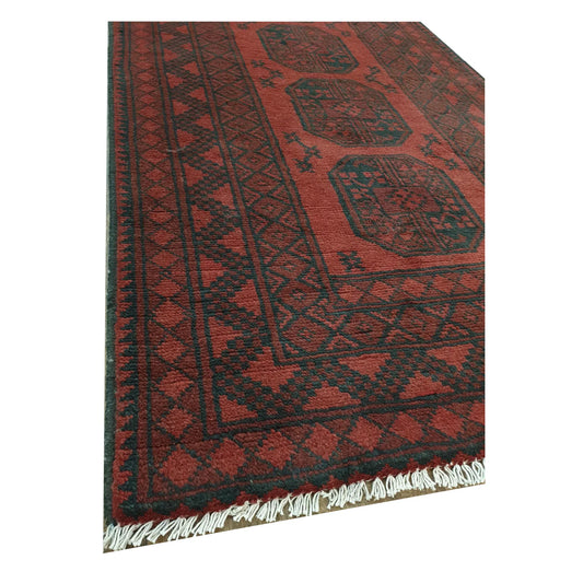 Close-up of Turkoman wool rug corner showing deep red border, fringe and hand-knotted texture