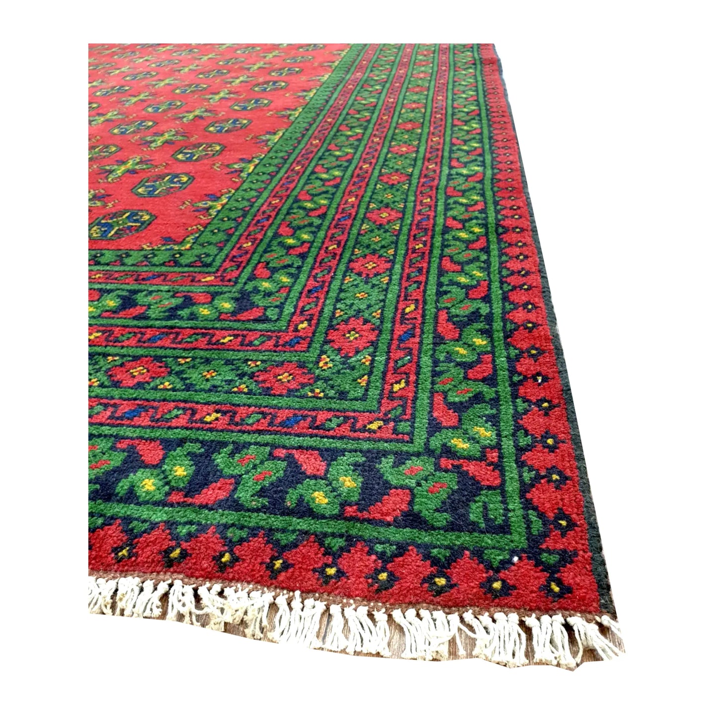 Angled corner of Afghan Turkoman rug showing layered red, green and navy borders with ivory fringe