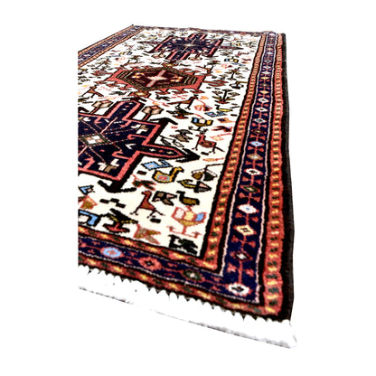 Angled view of vintage Afshar rug showing navy medallions, small animal and duck motifs, narrow patterned borders and white fringe