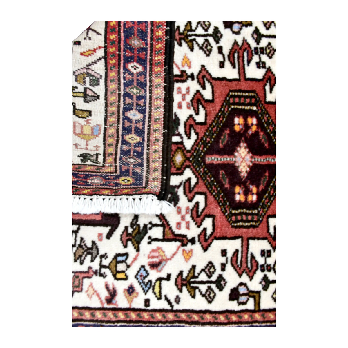 Folded-corner detail of vintage Afshar rug showing the patterned reverse beside its ivory animal-patterned front and white fringe