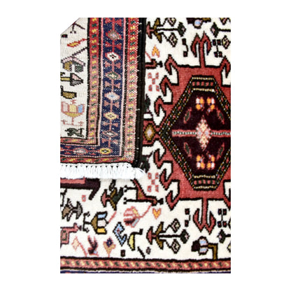 Folded-corner detail of vintage Afshar rug showing the patterned reverse beside its ivory animal-patterned front and white fringe