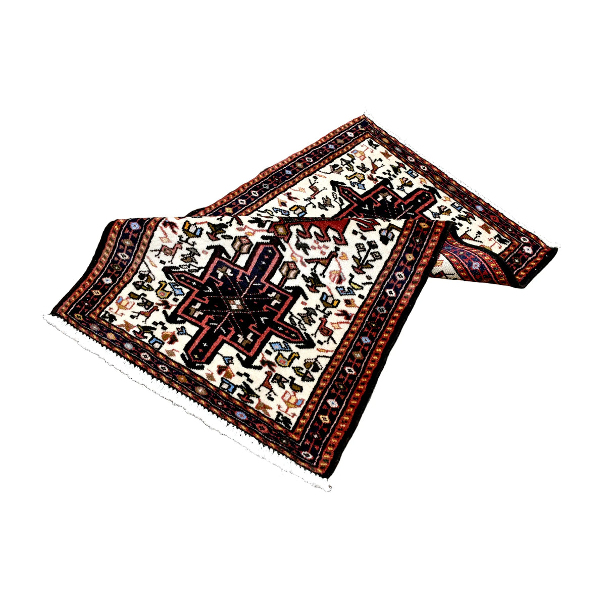 Folded view of vintage Afshar rug showing its ivory field, navy medallions, red geometric borders and exposed patterned reverse