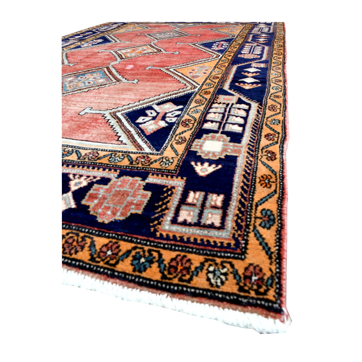 Angled view of Persian Afshar rug showing its brick-red field, linked diamond medallions, deep navy borders and pale fringe
