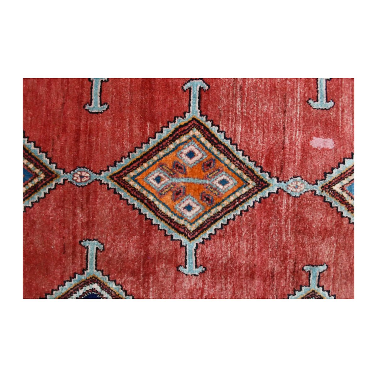 Close-up of an Afshar diamond medallion with a hooked outline and muted blue, mustard, ivory and terracotta details