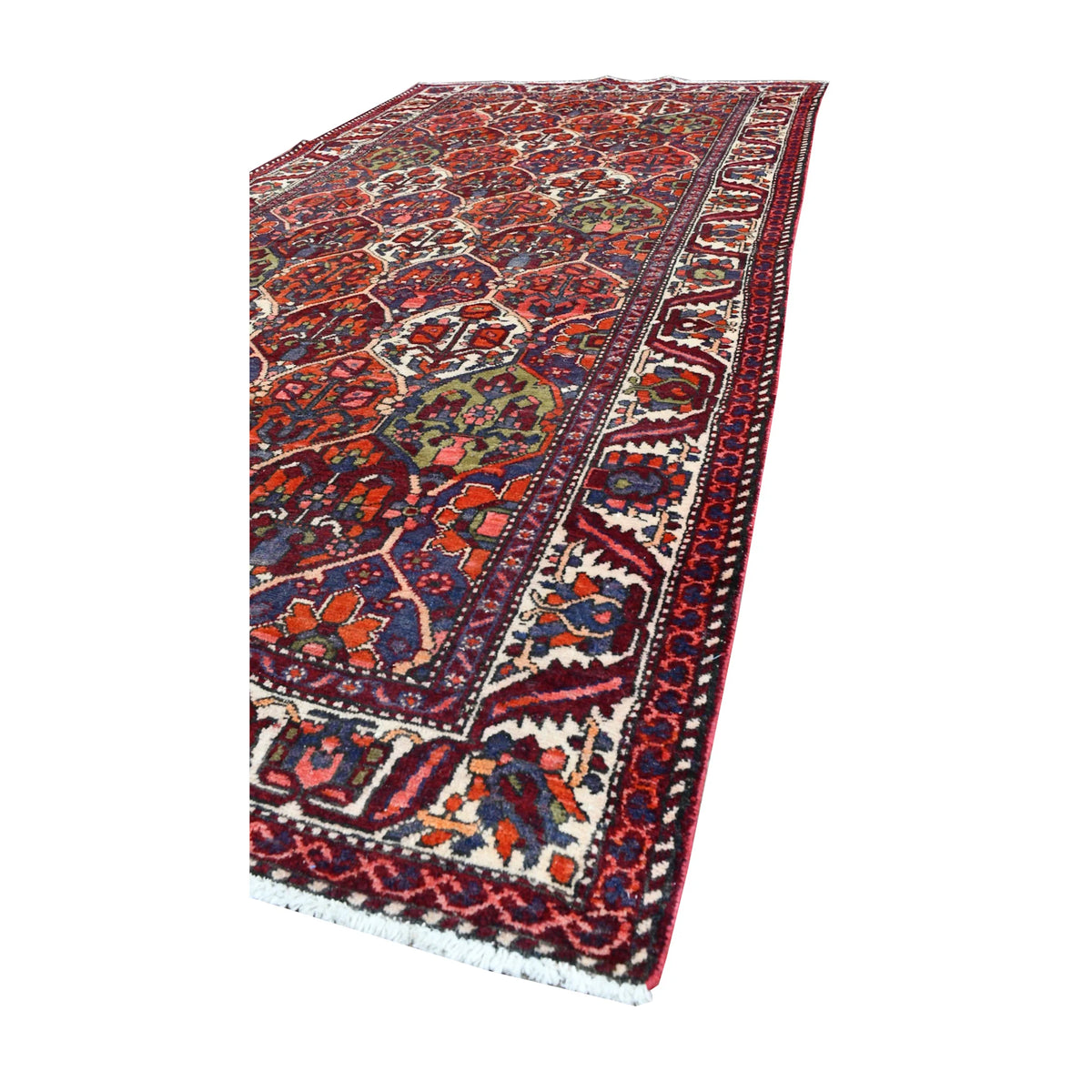 Lengthwise angled view of vintage Bakhtiari rug showing the wide ivory border around its multicolour garden-panel field
