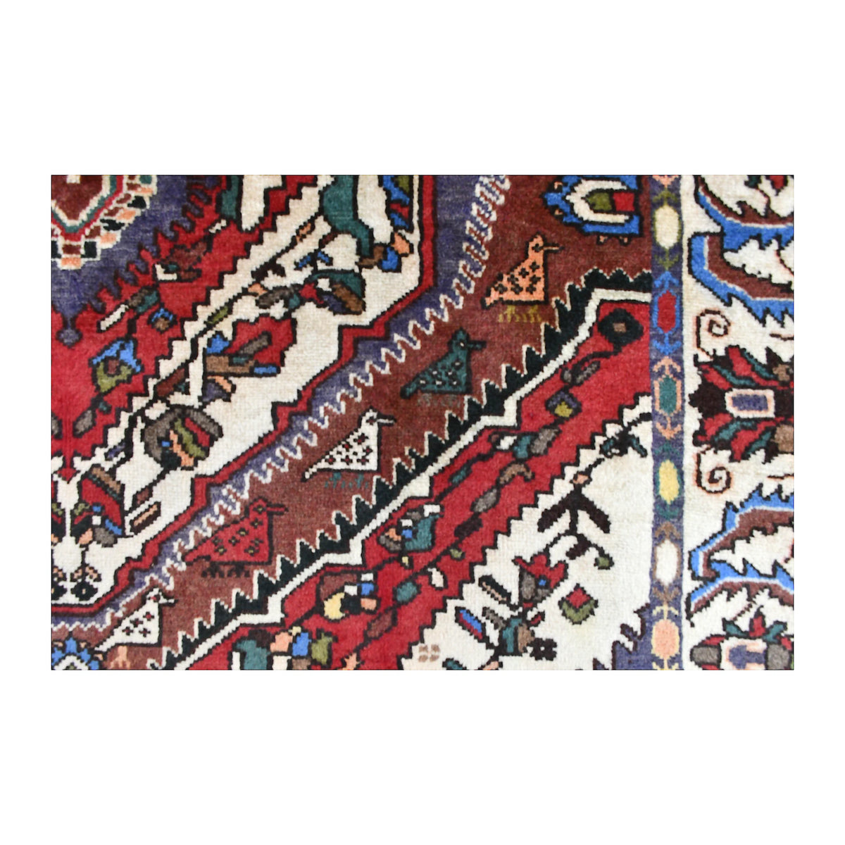 Close-up of Bakhtiari rug showing stepped red and brown bands, small floral forms and blue outlines against ivory