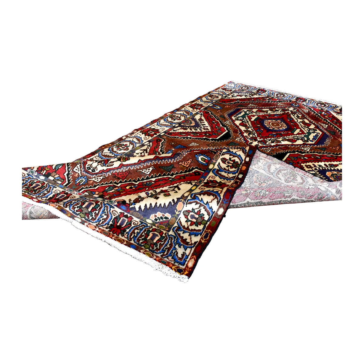 Folded view of vintage Bakhtiari rug showing the patterned front, pale reverse and floral border