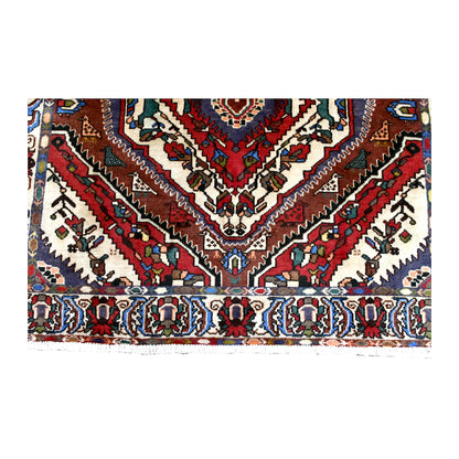 Fringe-end detail of Bakhtiari rug showing rust-red chevrons, pale floral spaces, patterned border and white fringe