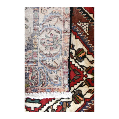 Reverse-weave detail of Bakhtiari rug showing its pale patterned back beside the floral-geometric front and white fringe