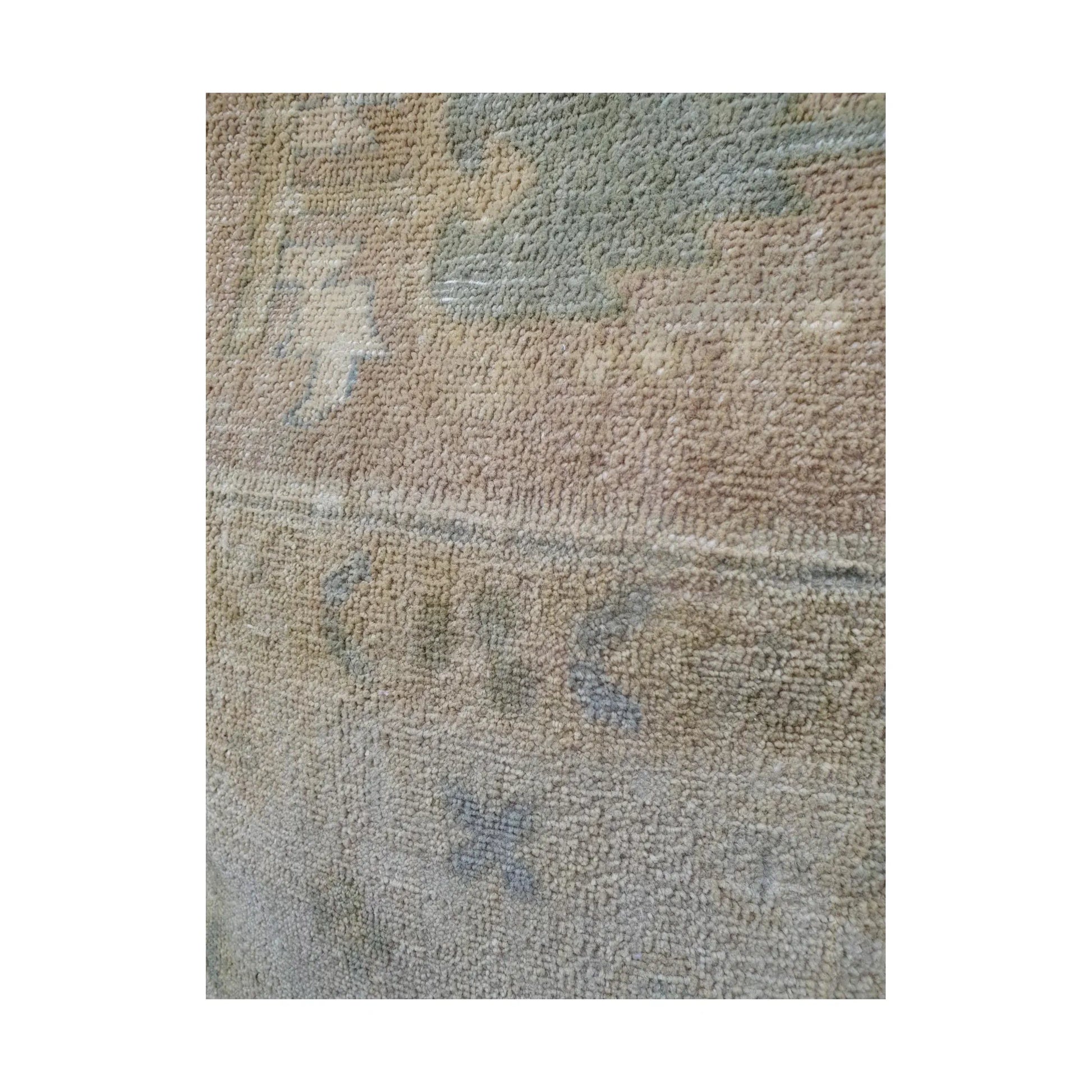 Close-up of muted sage-grey geometric motif and fine lines across the beige wool pile
