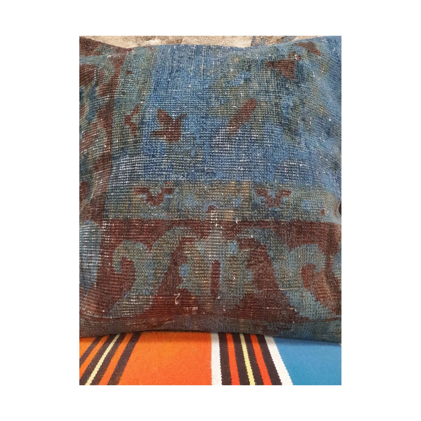 Close detail of blue and burgundy floral border fragments on the vintage Persian rug cushion cover