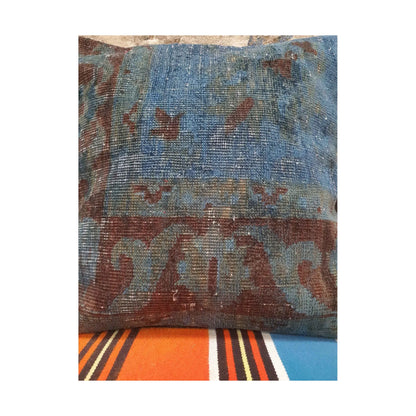 Close detail of blue and burgundy floral border fragments on the vintage Persian rug cushion cover