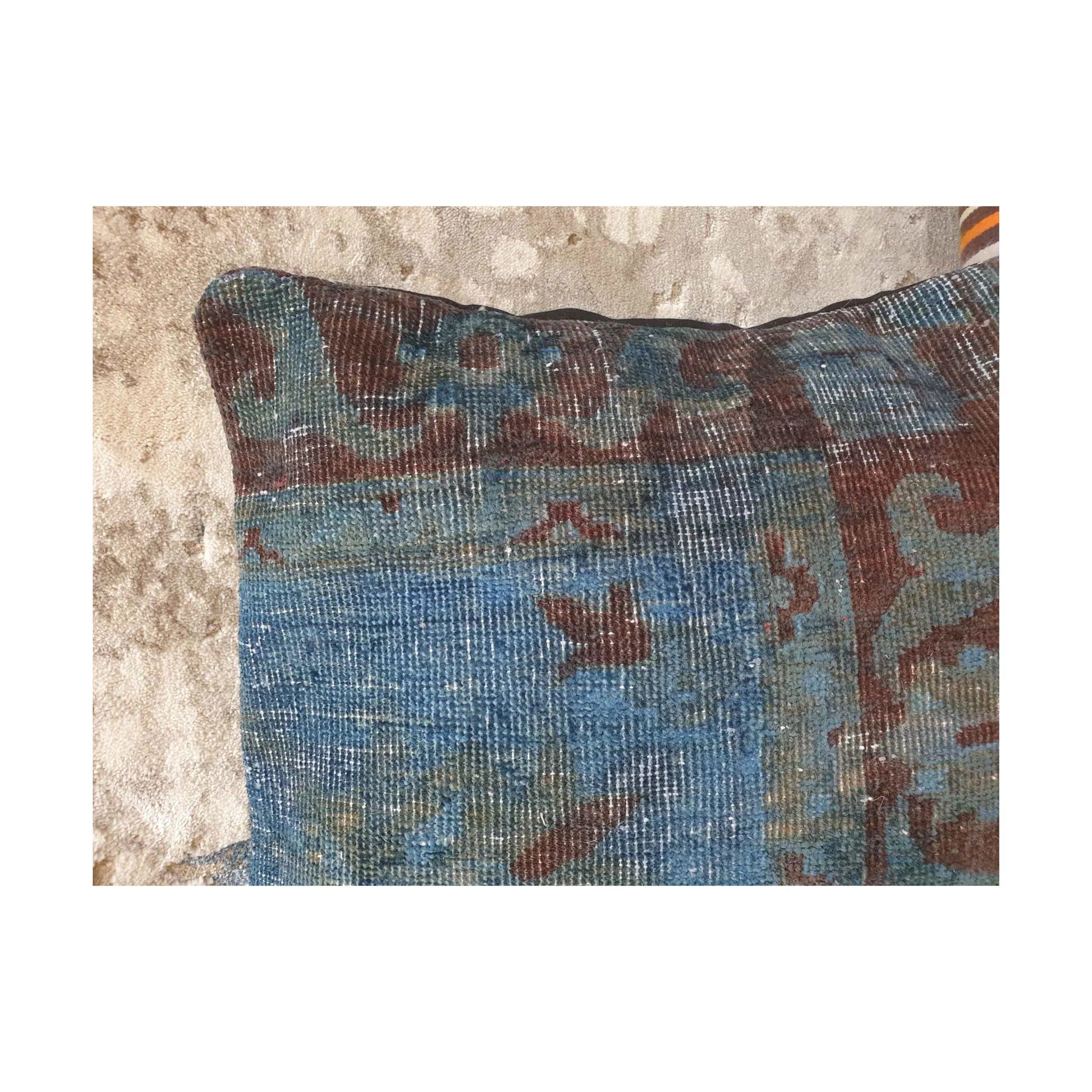 Close-up of dusty blue, muted blue-green and burgundy patterning across the upper section of the Persian cushion cover