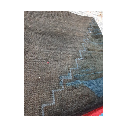 Angled close-up of dark charcoal wool pile and muted blue stepped lines on the Persian cushion cover