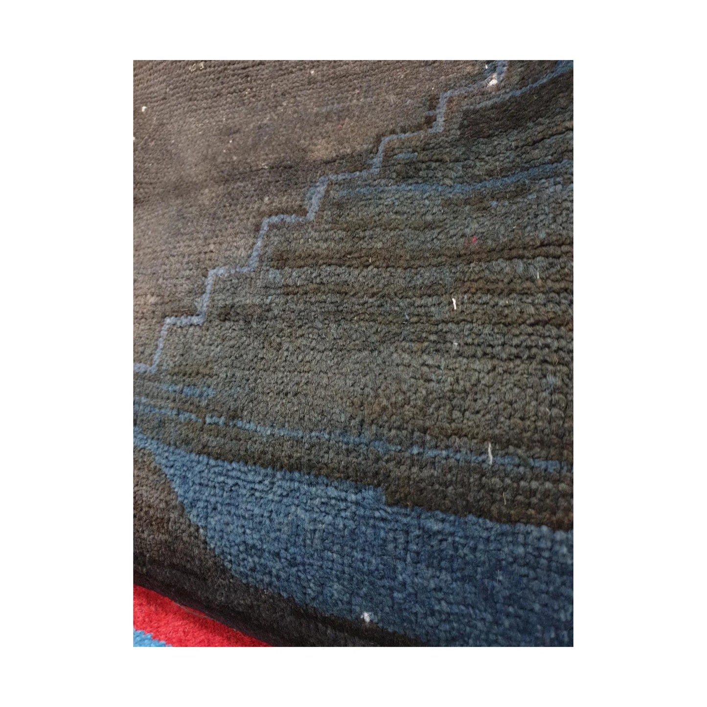 Close-up of muted blue geometric bands across the dark charcoal wool pile