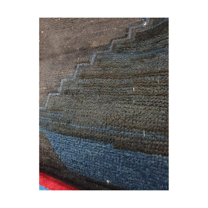 Close-up of muted blue geometric bands across the dark charcoal wool pile