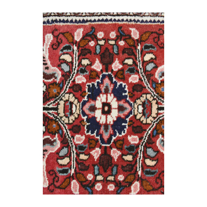 Central medallion detail of vintage Persian Hamadan wool rug showing deep red field, ivory animal motifs and dark outlined pattern