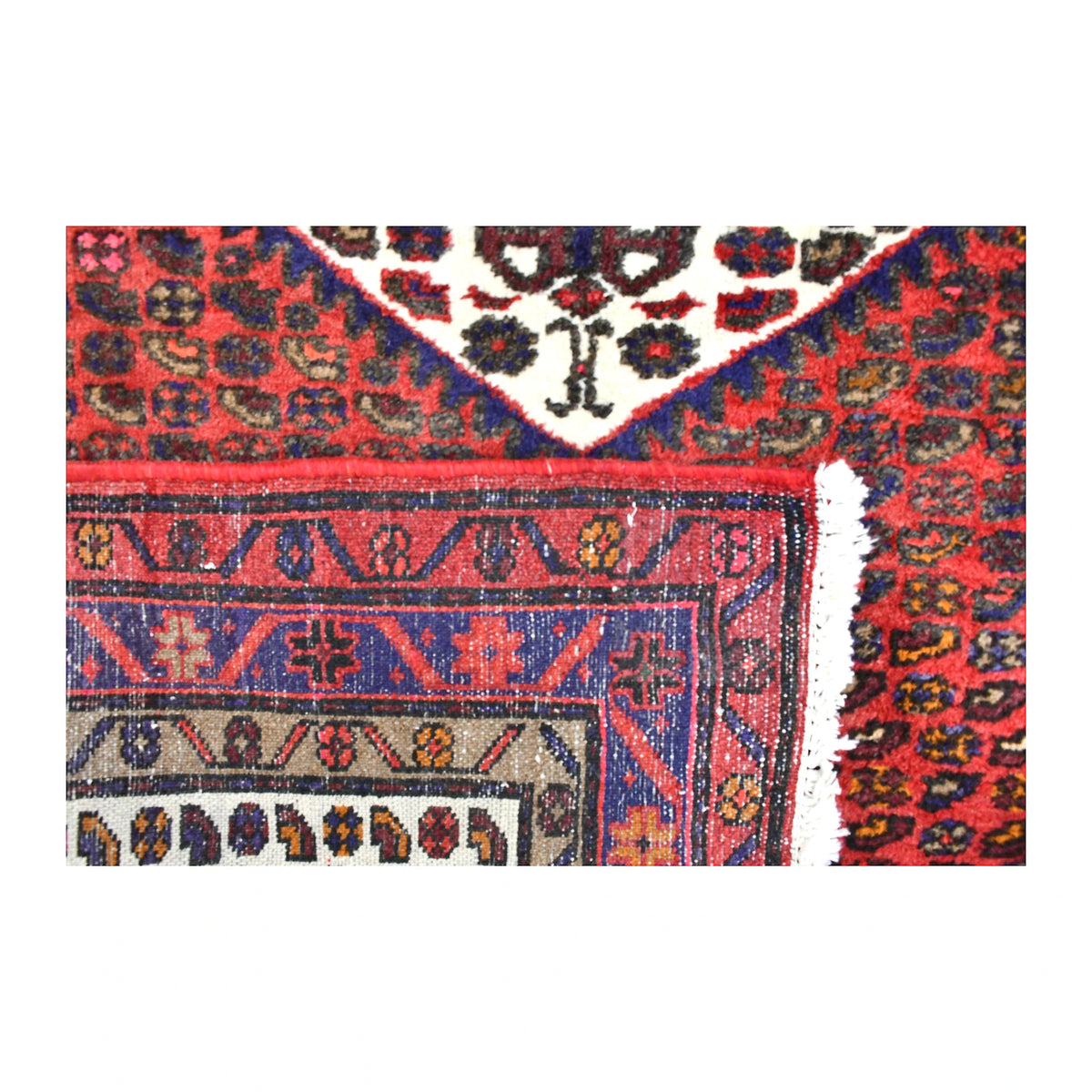 Folded-corner detail of Persian Hamadan rug showing the reverse weave, layered border and pale fringe