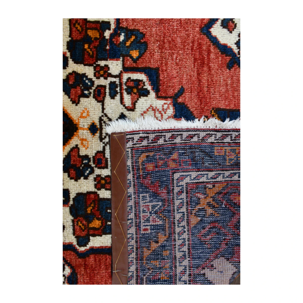 Folded-corner detail of Persian Hamadan rug showing the reverse weave, floral front and pale fringe