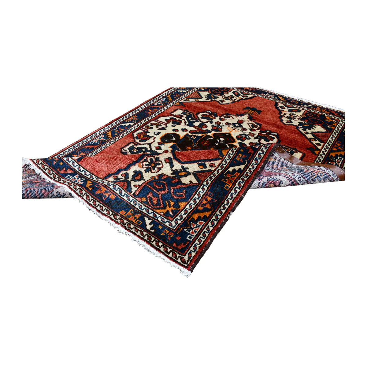 Folded view of vintage Persian Hamadan hand-knotted wool rug showing its medallion field, border and fringe
