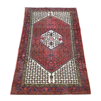 Angled full view of vintage Persian Hamadan rug showing red geometric medallion design