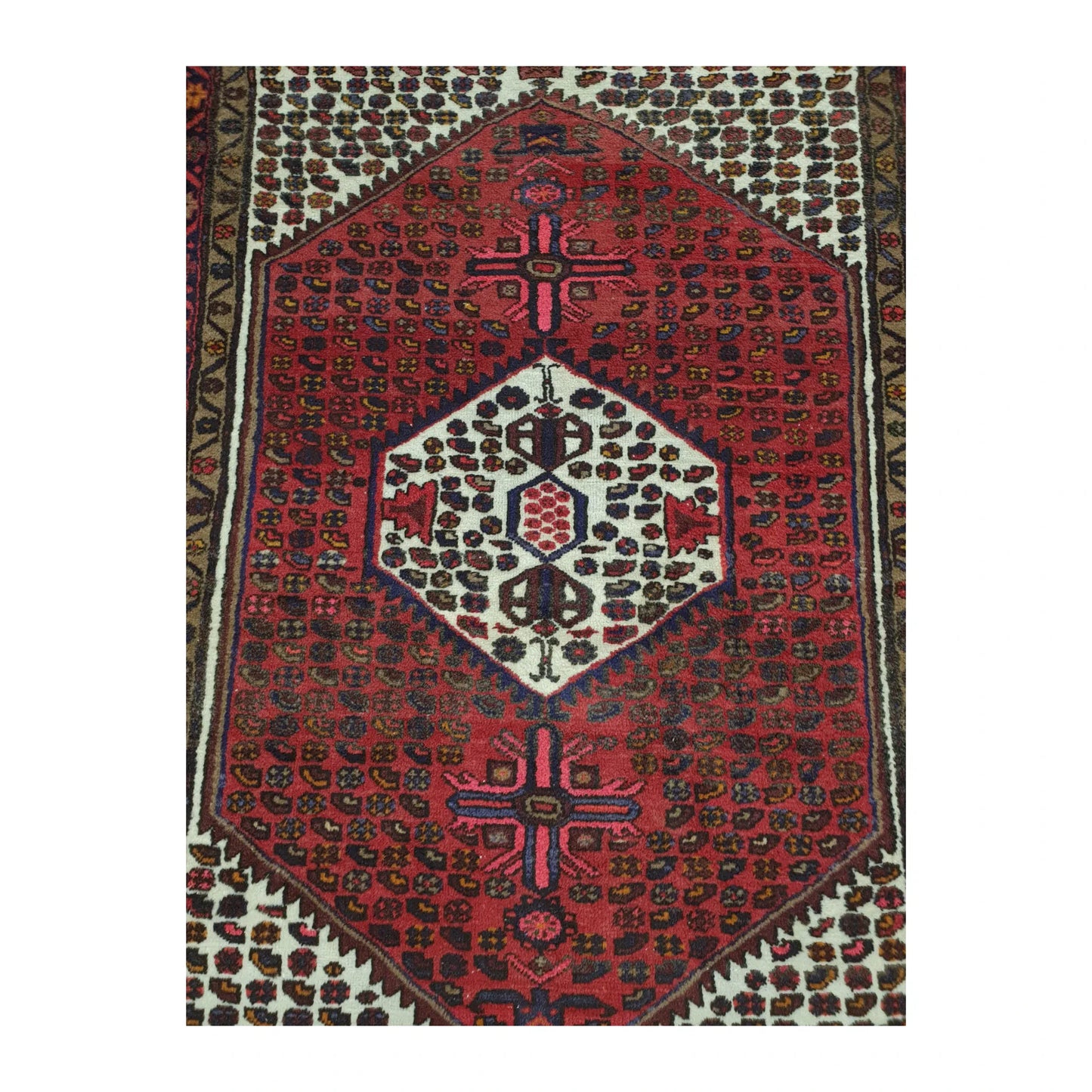 Close-up of Persian Hamadan rug showing red central medallion and cream patterned field