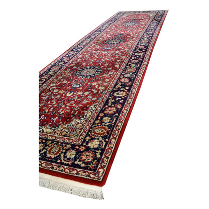 Lengthwise angled view of vintage Kashan runner showing repeating floral medallions along the red field