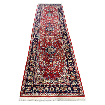 Full view of vintage Persian Kashan hand-knotted wool runner with a red floral field, blue medallions and navy border, 350 x 92 cm
