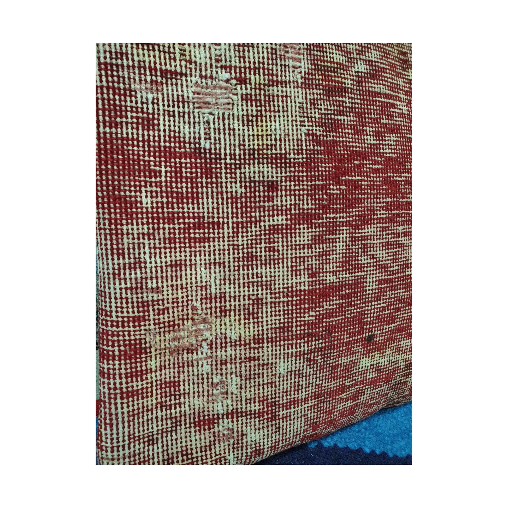 Detailed view of irregular red and ivory crosshatching across the hand-knotted wool pile